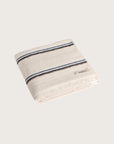 Købn Ecru Towel with blue and tan stripes featuring raw edge fringing folded