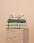 Matcha bathroom set folded on a travertine plinth with a clam shell on top.