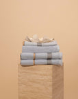 Stack of Mist Bathroom towels , hand towel and bathmat folded on a travertine plinth.