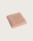 Folded pink bathmat on a light beige background