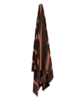 Dark brown towel with red stripes hanging on blank wall.