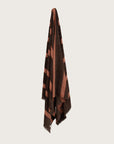 Købn Umber Towel with stripes and raw edge fringing hanging on a hook