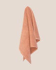 Textured chunky weave bathmat in a neutral clay colour hanging on a butter yellow background.