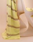 Citrus towel by Kobn with brown stripes draped over a chair on a beige background