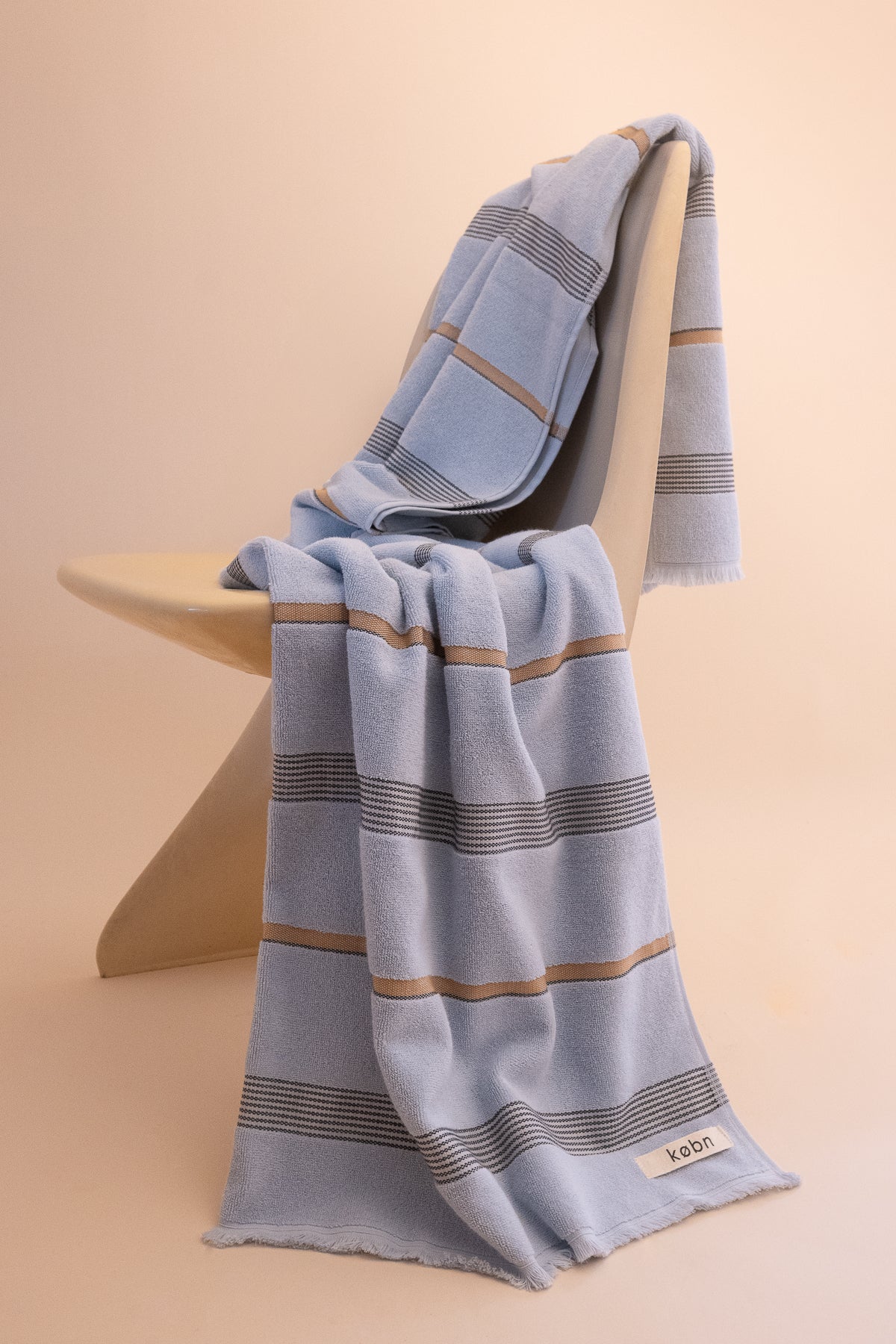Mist striped towel with variegated stripes draped over a vintage Casalla chair