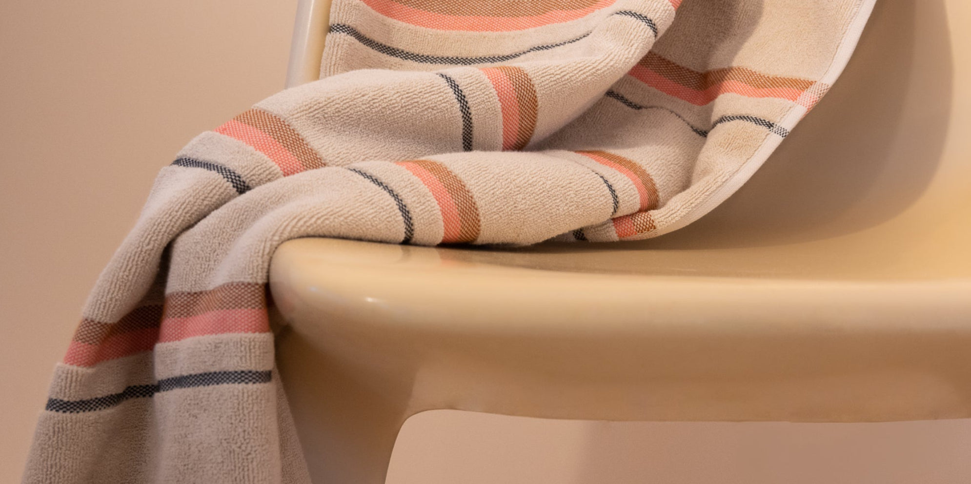 Kobn Sand towel with stripes draped on a chair.