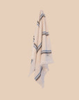 Ecru hand towel with blue stripes hanging on hook with butter yellow background