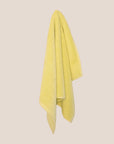 Textured yellow bathmatl hanging against a beige background