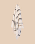 White hand towel with black stripes and 'kobn' branding on a beige background