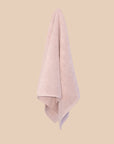 Textured lilac bathmat hanging on a neutral background