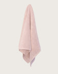 Textured lilac bathmat hanging on a neutral background