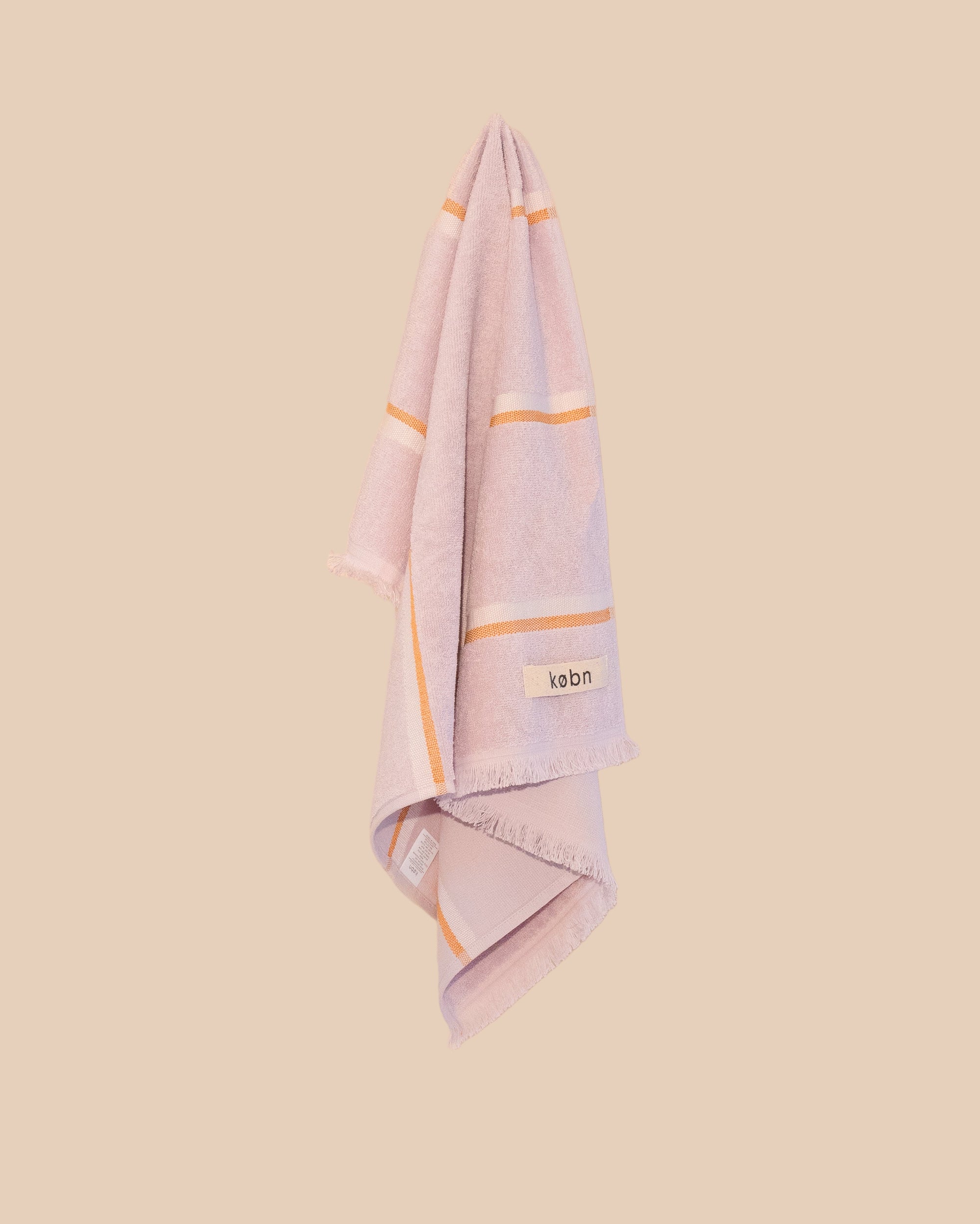 Lilachand towel with orange stripes and 'kobn' logo on a beige background