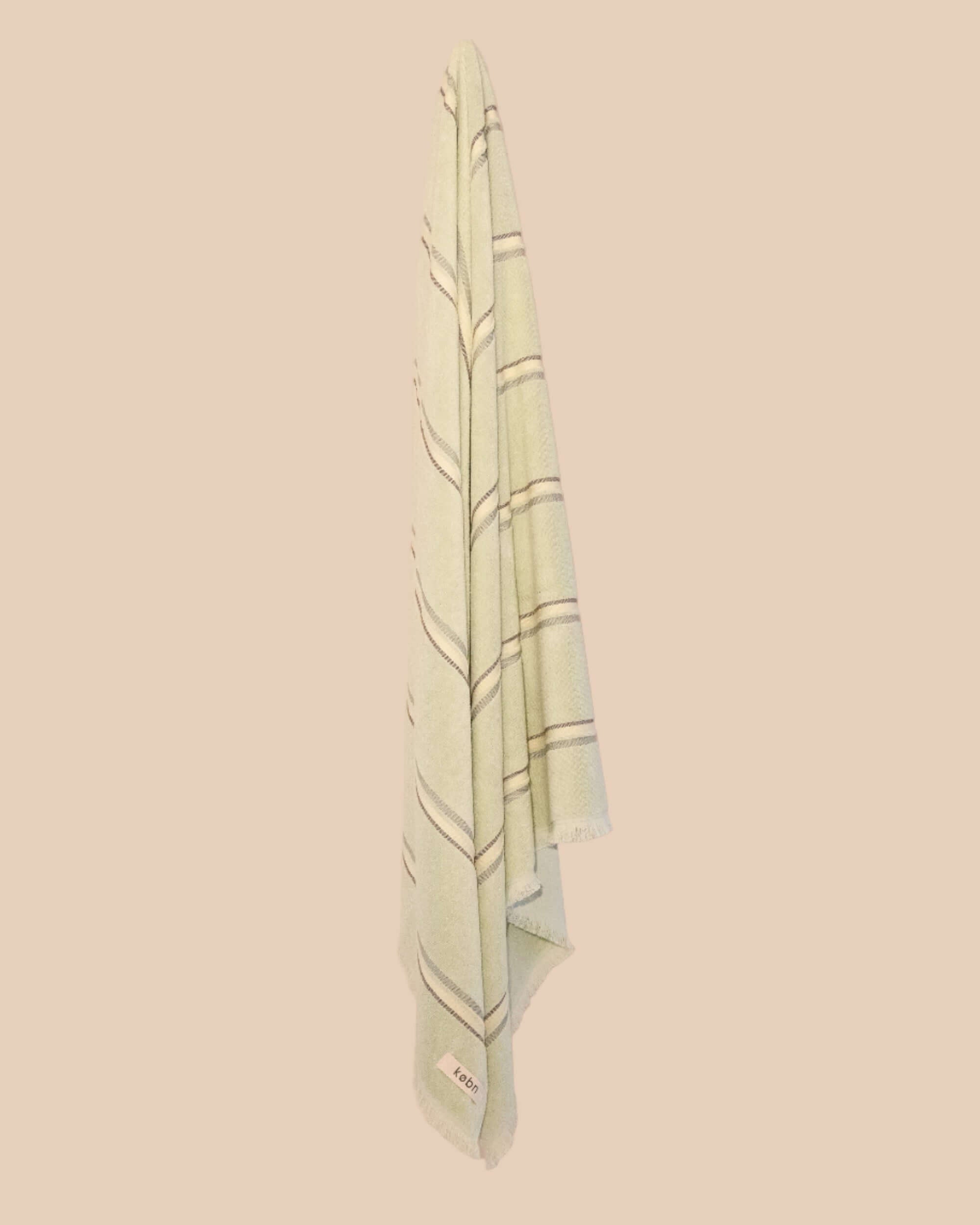 Light green towel with stripes hanging on a neutral background wall.