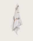Pale Blue hand towel with stripes and fringing hanging on a butter yellow wall.