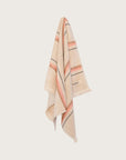 striped hand towel in sand colour with a hot pink and tan stripe hanging on a neutral background.