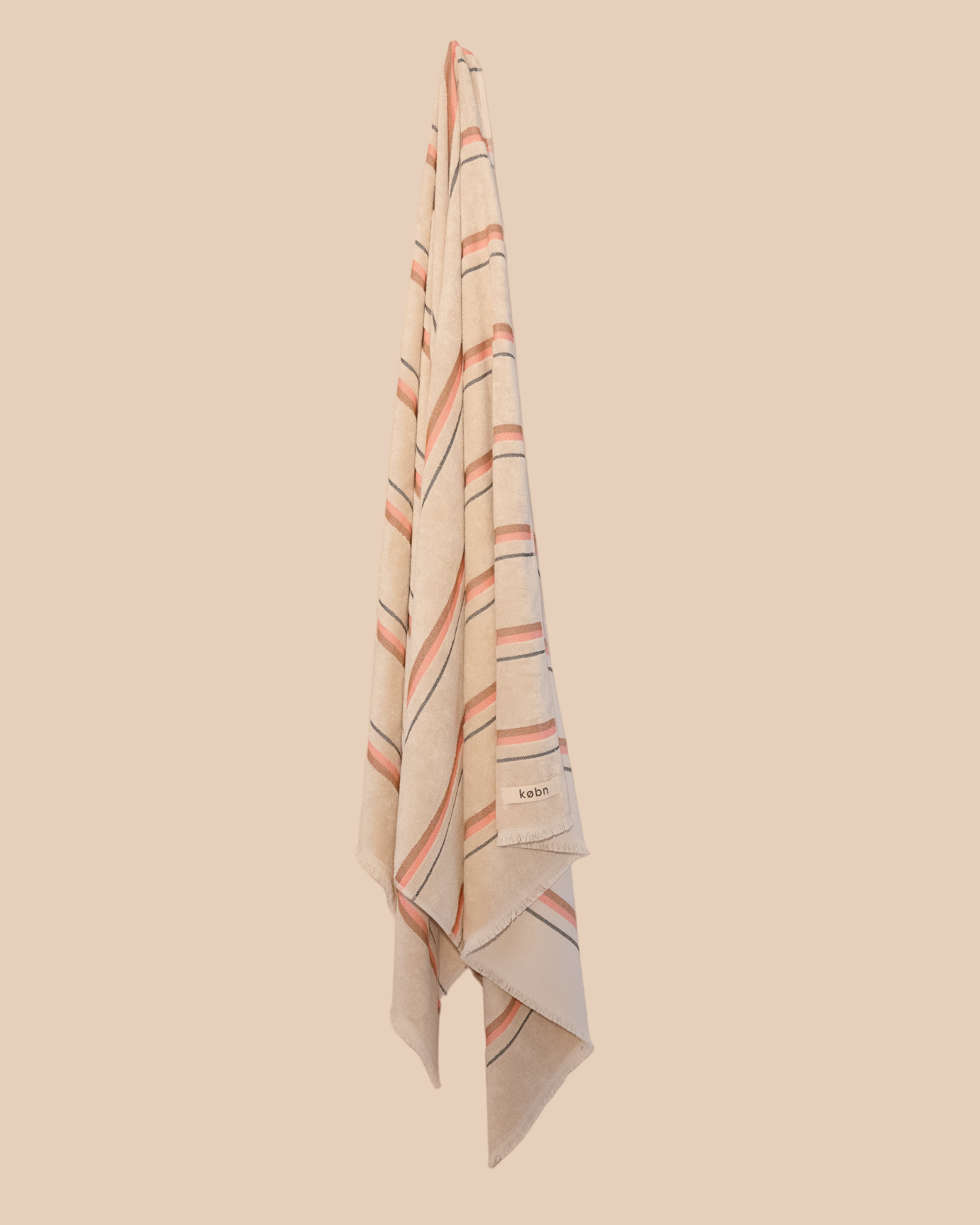 Striped kobn towel with pink and tan stripes on a beige background