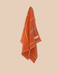 Tamarillo hand towel hanging with stripes and raw edge fringing.