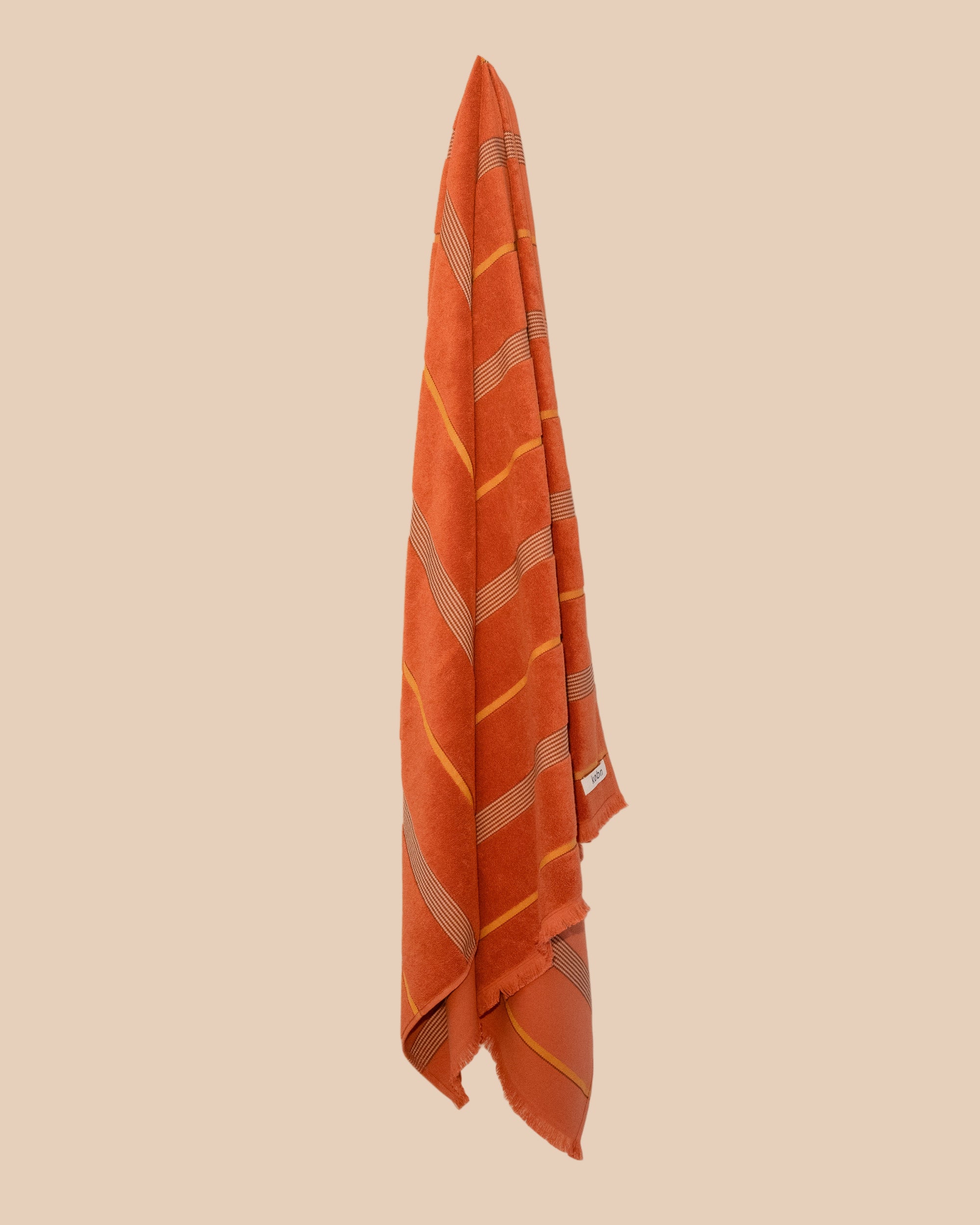 Tamarillo turkish towel hanging ith stripes in yellow and brown.