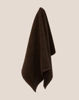 Brown textured bathmat hanging on a beige wall