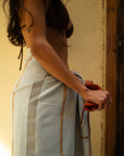 Woman with a striped pale blue towel around her waist and bikini top and yellow textured wall