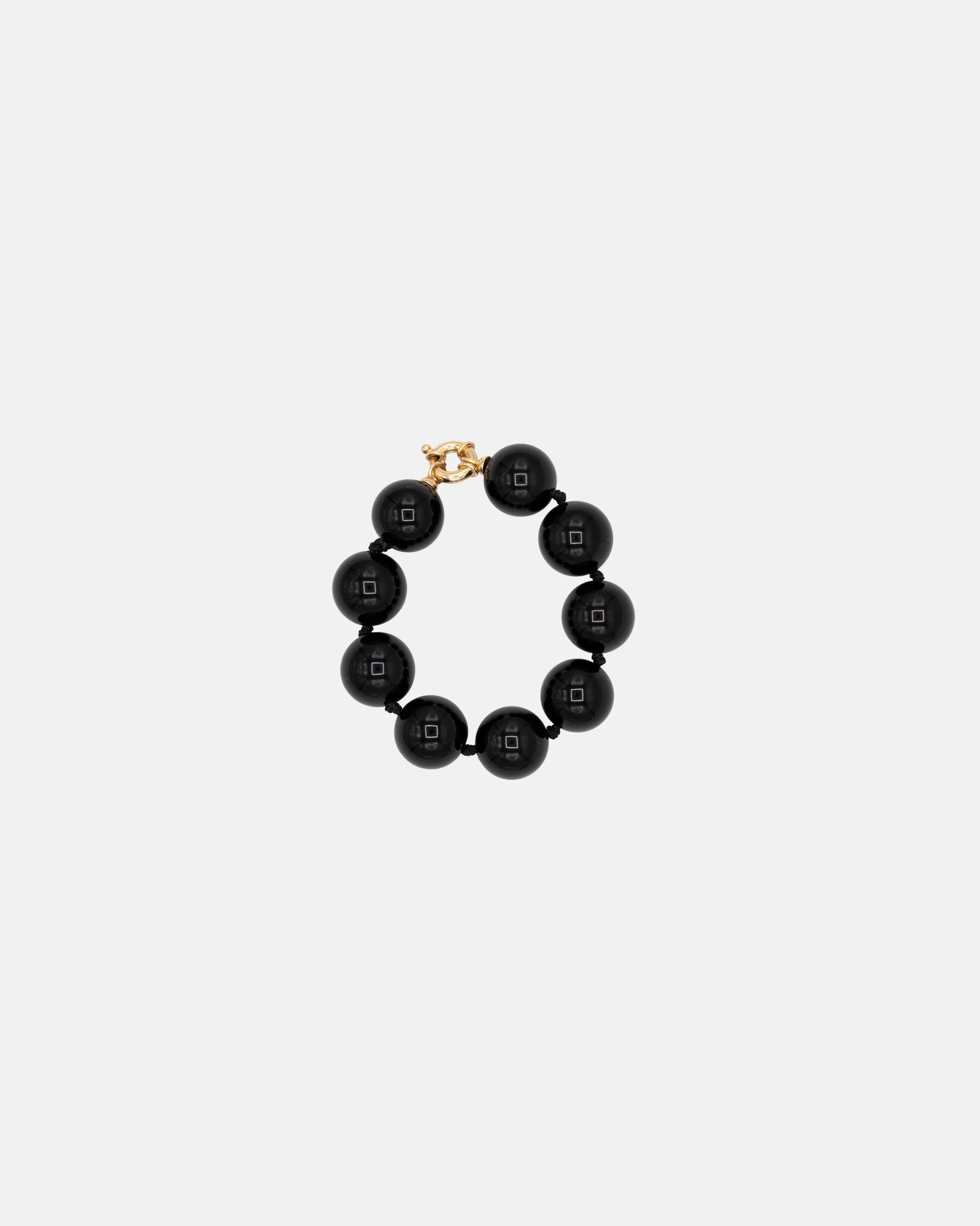 Black beaded bracelet with gold clasp on a white background