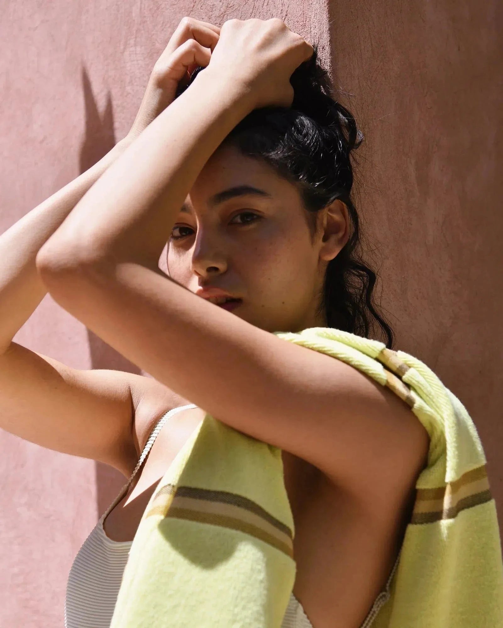 A woman holding her hands on her head with a Citrus towel with stripes draped on her shoulder. 