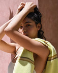 A woman holding her hands on her head with a Citrus towel with stripes draped on her shoulder. 