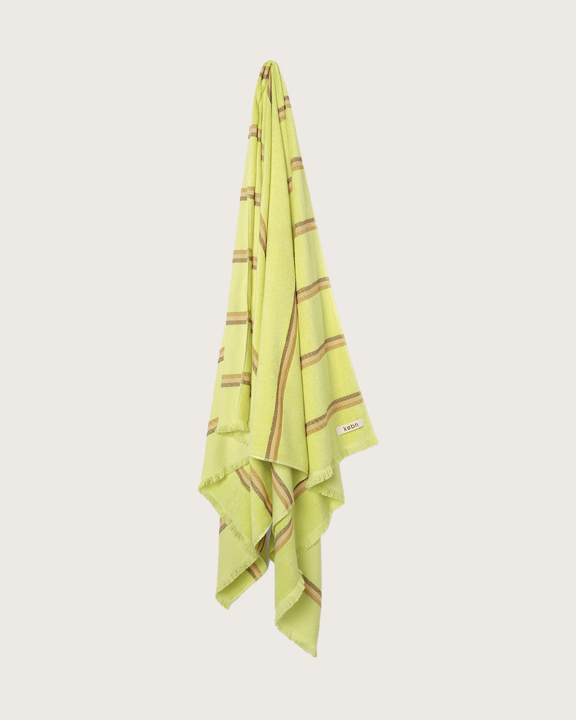 Købn Citrus Towel stripes and raw edge fringing hanging on a hook