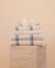 Stack of Kobn towels, bathmat and hand towel in Ecru featuring blue and tan stripes. 