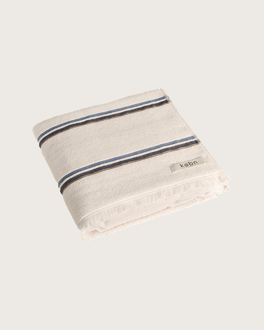 Købn Ecru Towel with blue and tan stripes featuring raw edge fringing folded 