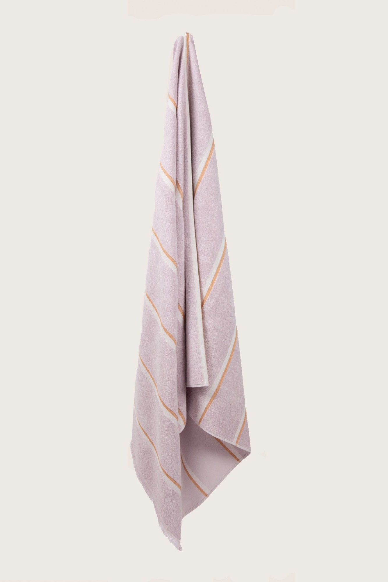 Købn Lilac Towel with stripes and raw edge fringing hanging on a hook