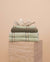 Matcha bathroom set folded on a travertine plinth with a clam shell on top.