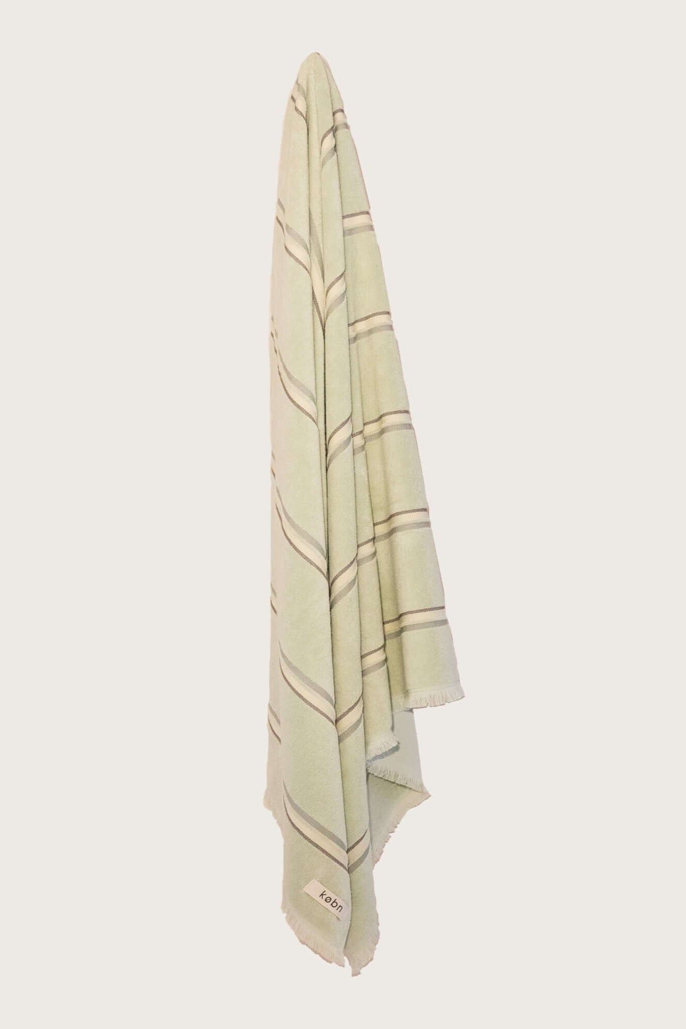 Købn Match Towel with stripes and raw edge fringing hanging on a hook