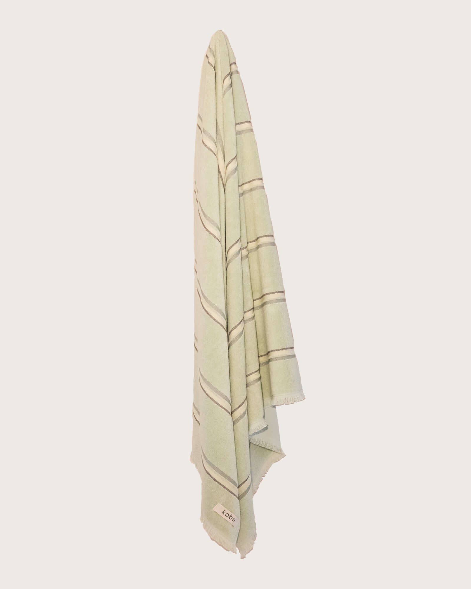 Købn Match Towel with stripes and raw edge fringing hanging on a hook