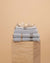 Stack of Mist Bathroom towels , hand towel and bathmat folded on a travertine plinth. 