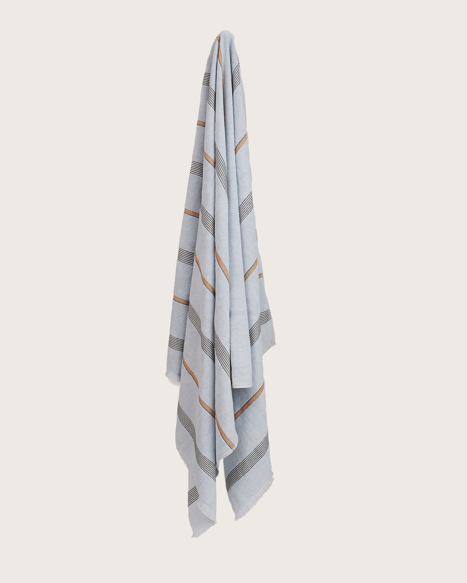 Købn Mist Towel with stripes and raw edge fringing hanging on a hook