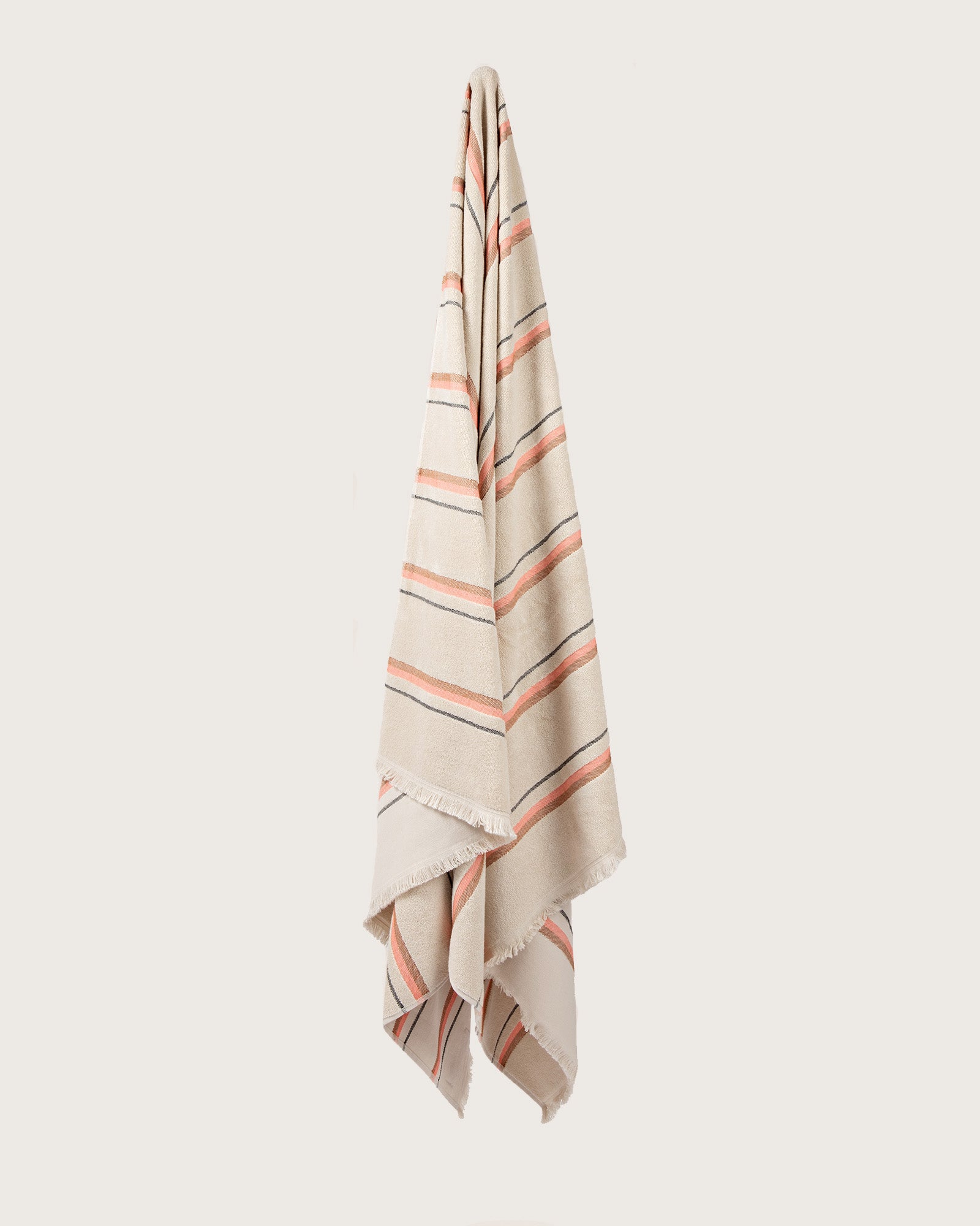 Købn Sand Towel with stripes and raw edge fringing hanging on a hook