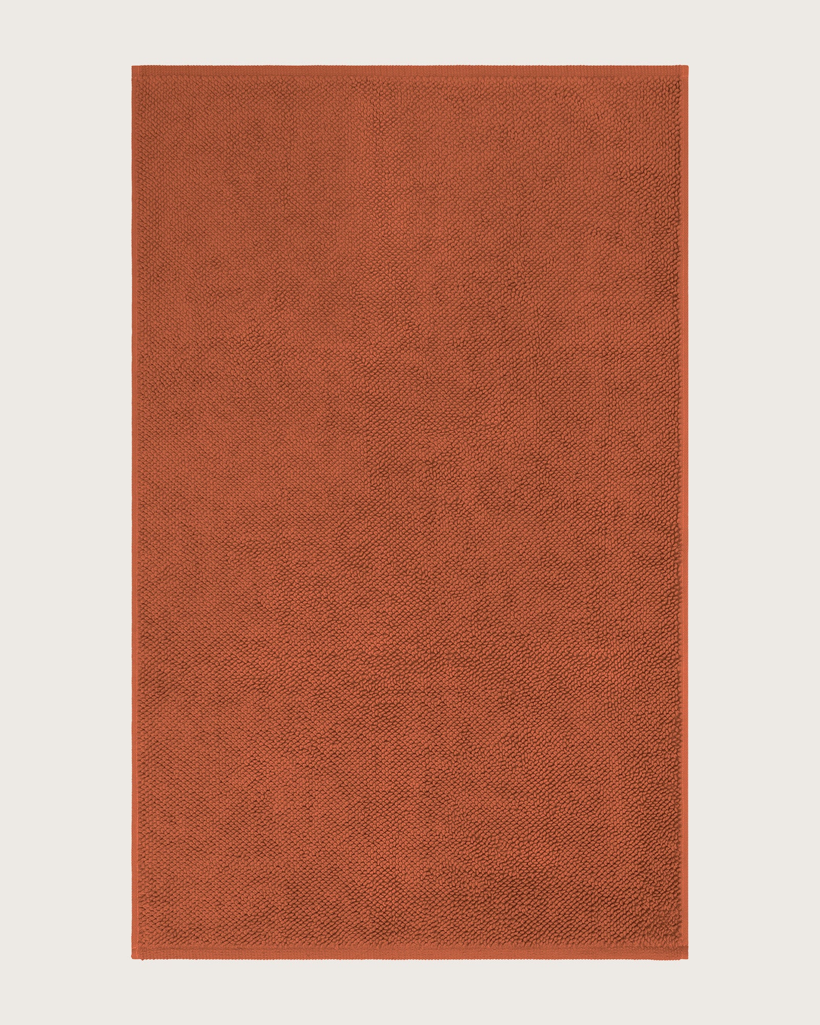Rectangular orange bathmat on a light beige background