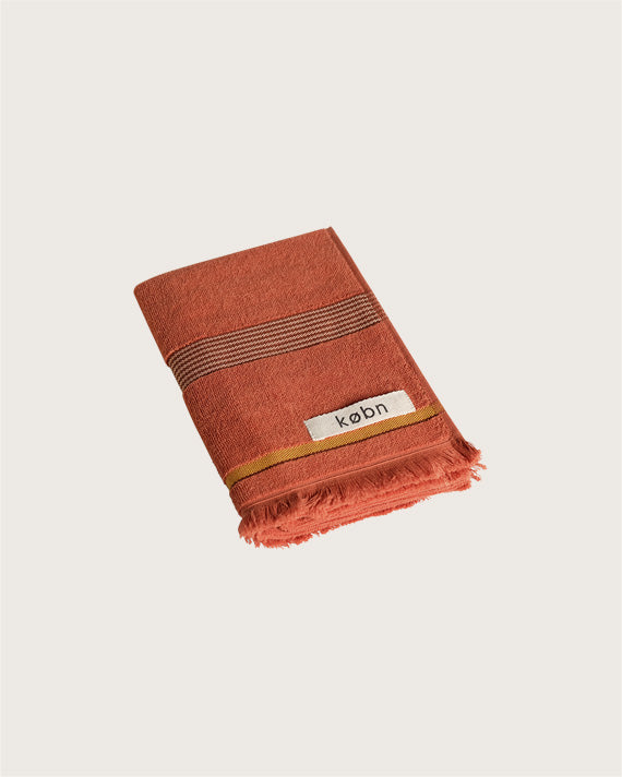 Købn Tamarillo Hand Towel featuring raw edge fringing folded 