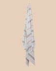Pale Blue Beach Towel with stripes hanging on a butter yellow background
