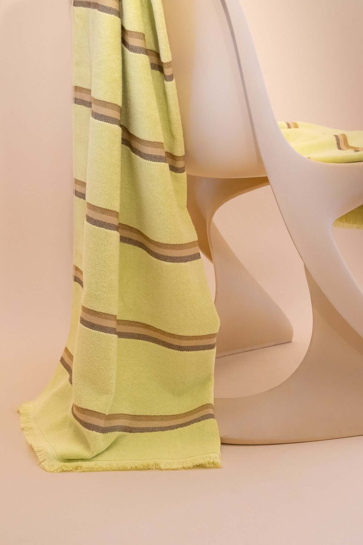 Citrus  towel by Kobn with brown stripes draped over a chair on a beige background