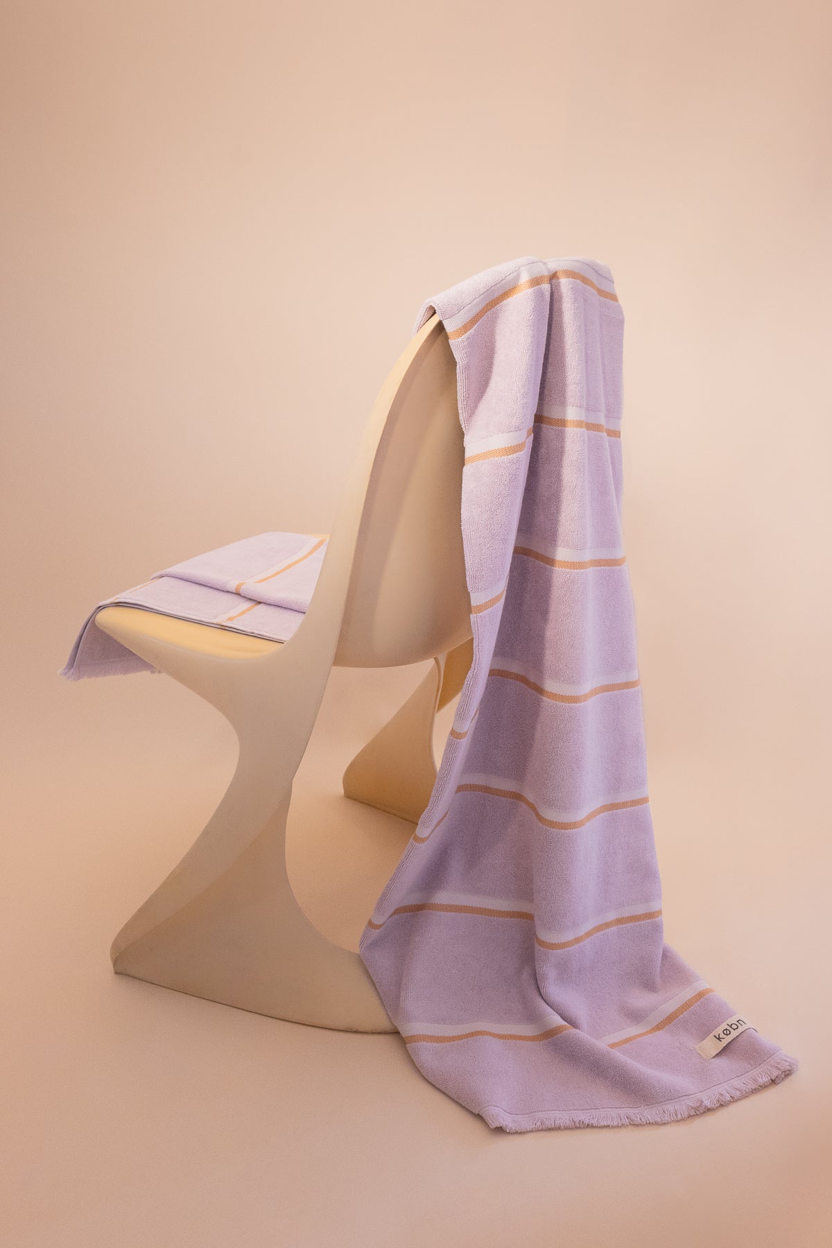 Luxury cotton towel by kobn in Lilac with a stripe draped on an original Casala Dining Chair