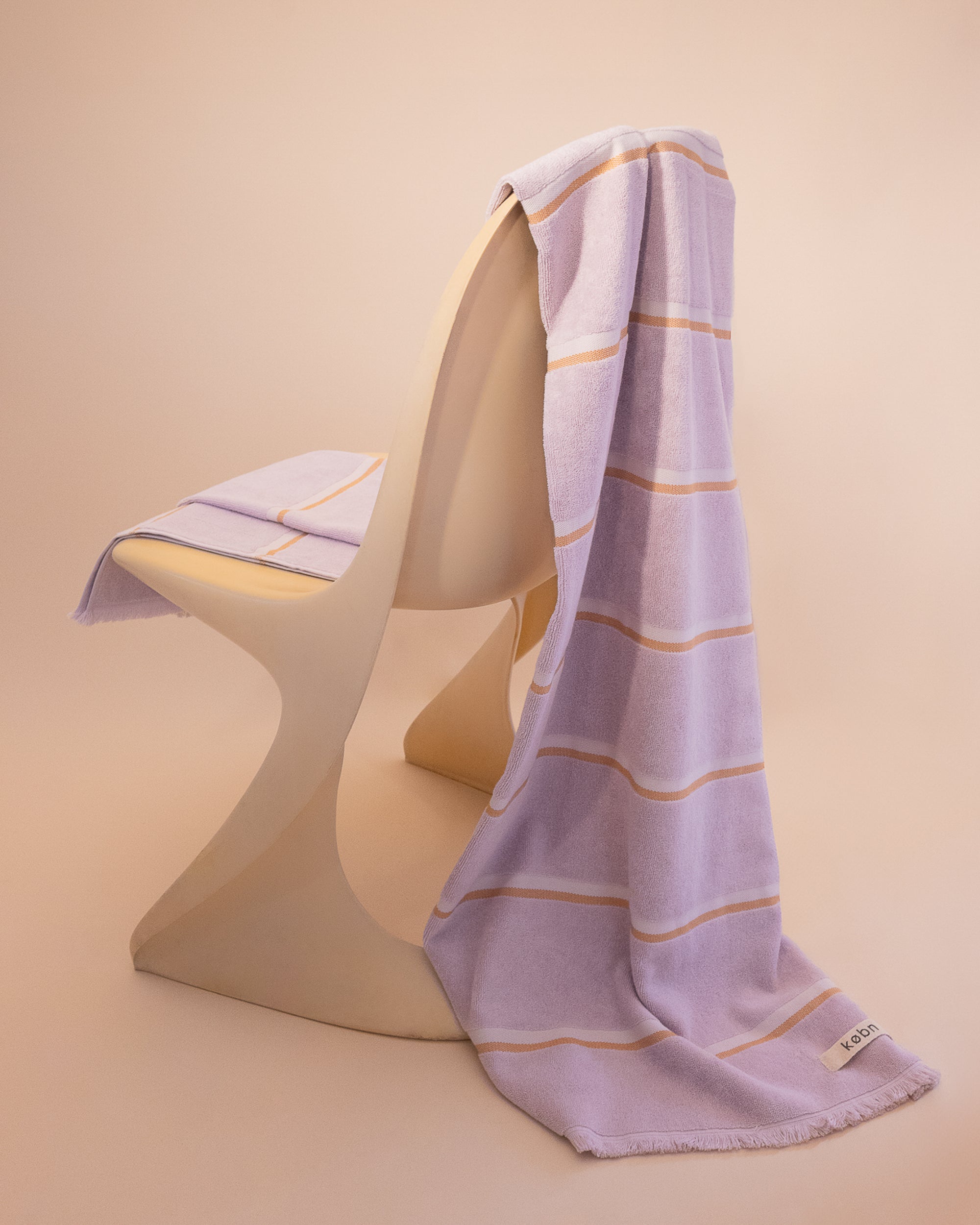 Luxury cotton towel by kobn in Lilac with a stripe draped on an original Casala Dining Chair
