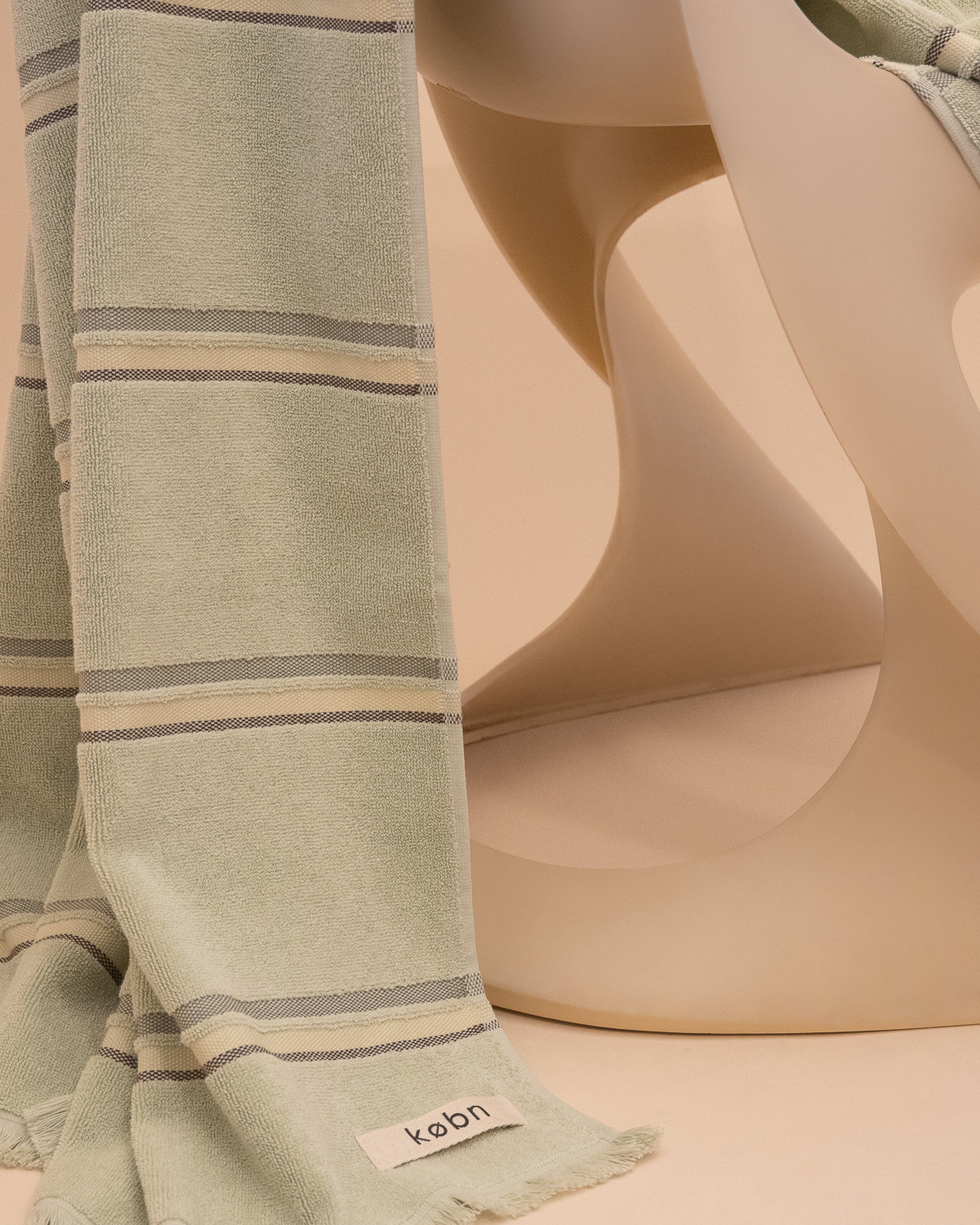 Kobn new season Matcha coloured striped towel draped on a chair