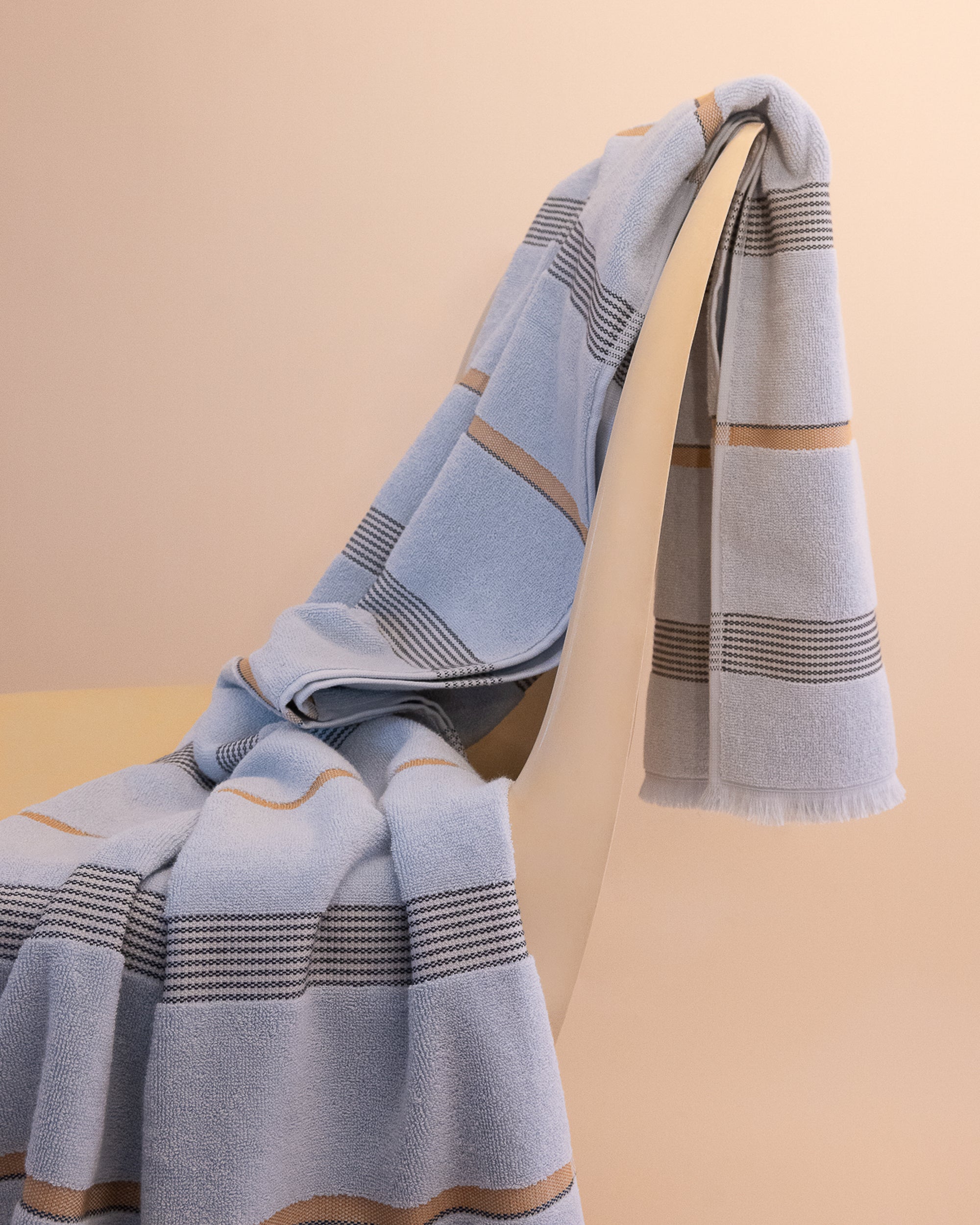 Luxury Mist towel with stripes draped on a chair