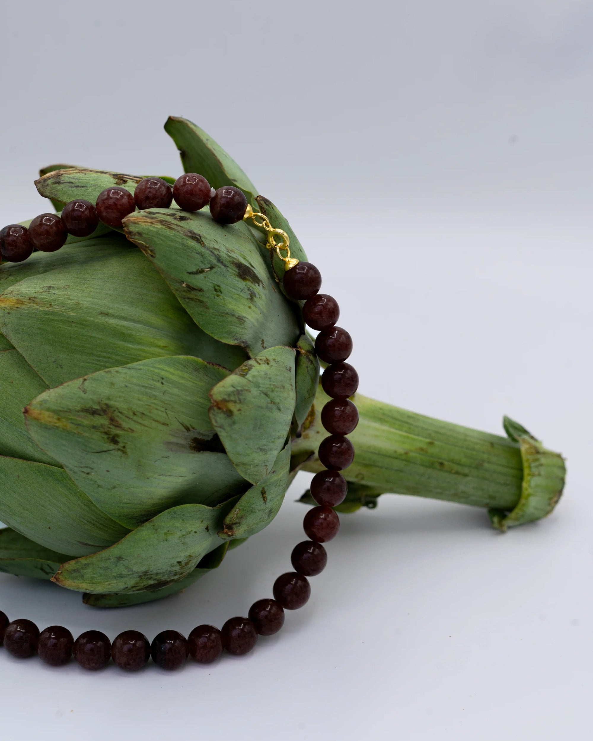 Artichoke with a quartz necklace on a white background