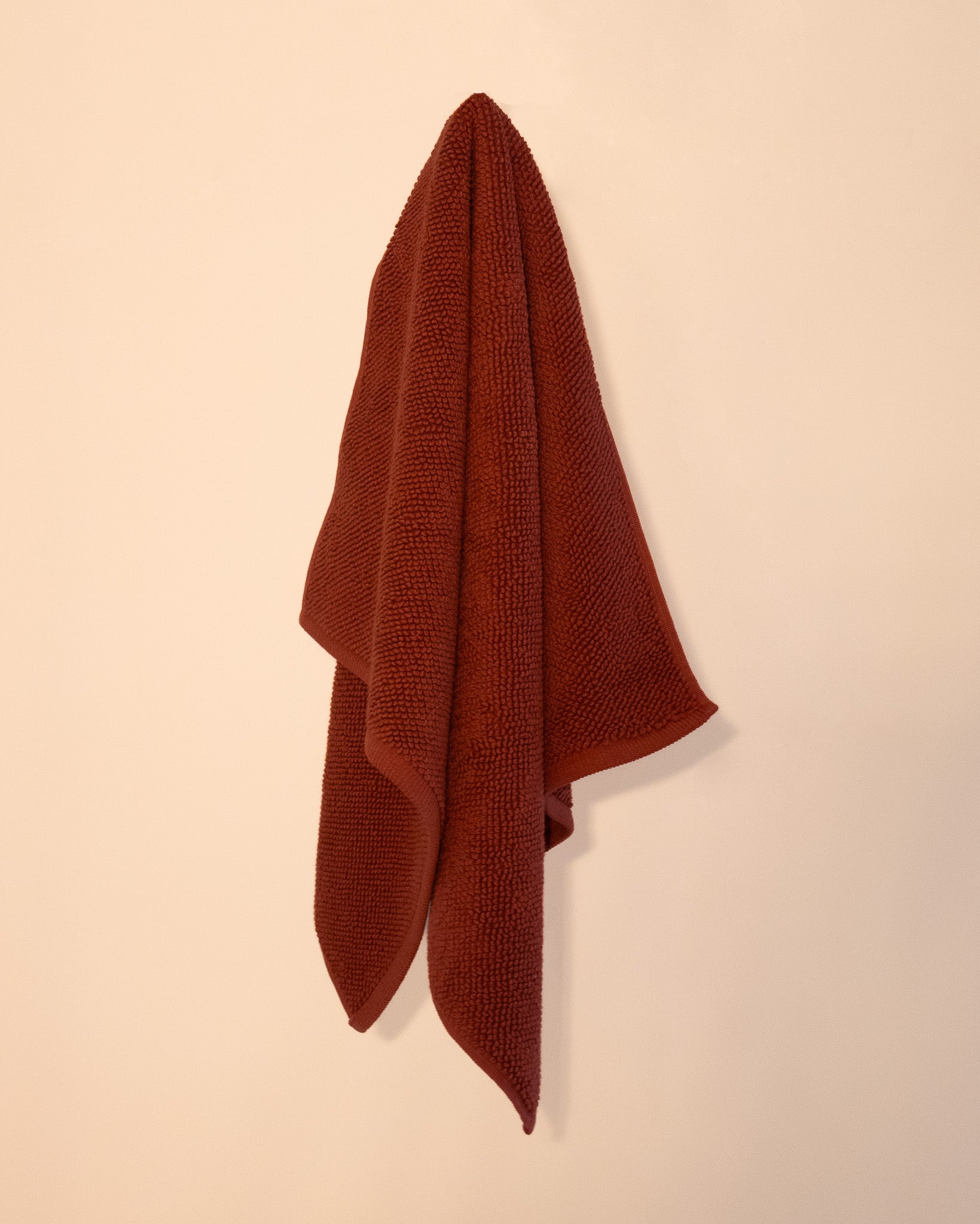 Cotton bathmat hanging on cream wall