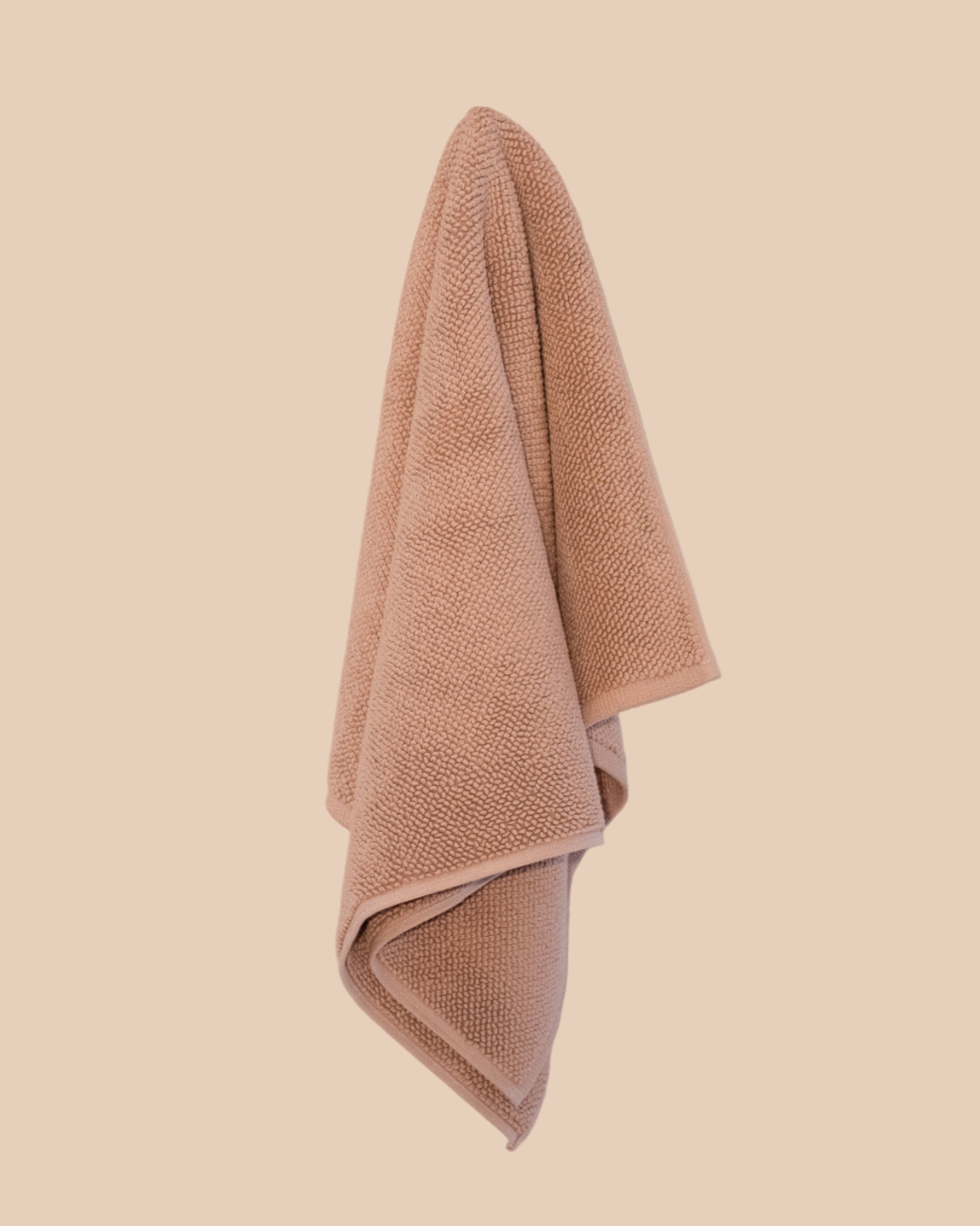 chunky cotton weave bathmat in nougat colour hanging on a butter yellow background. 