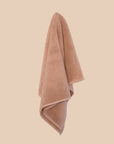 chunky cotton weave bathmat in nougat colour hanging on a butter yellow background. 