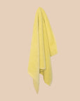 Textured yellow bathmatl hanging against a beige background